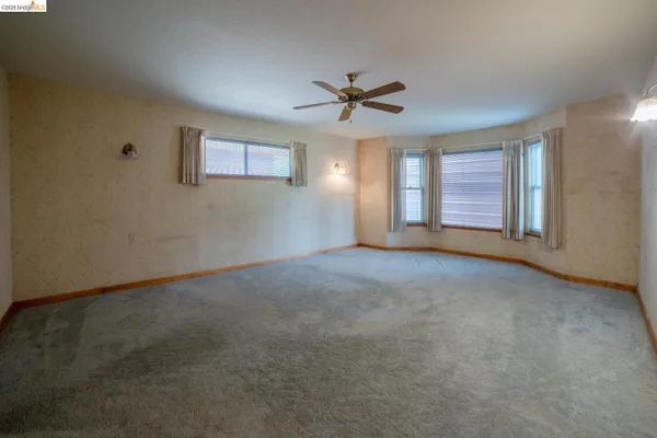 a view of a big room with windows and chandelier fan