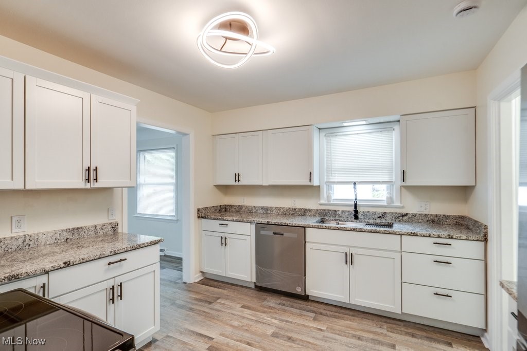 6961 Maplewood Road Parma Heights, OH 44130 - Photo 6 of 22 Kitchen featuring stainless steel dishwasher, light hardwood / wood-style flooring, white cabinetry, and a wealth of natural light