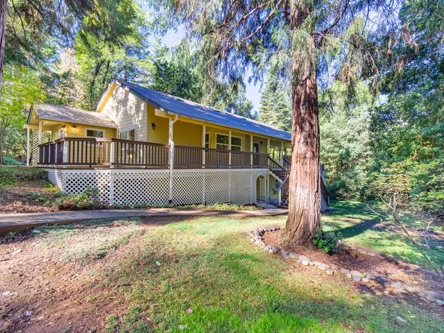 a view of a house with a wooden deck and a large tree