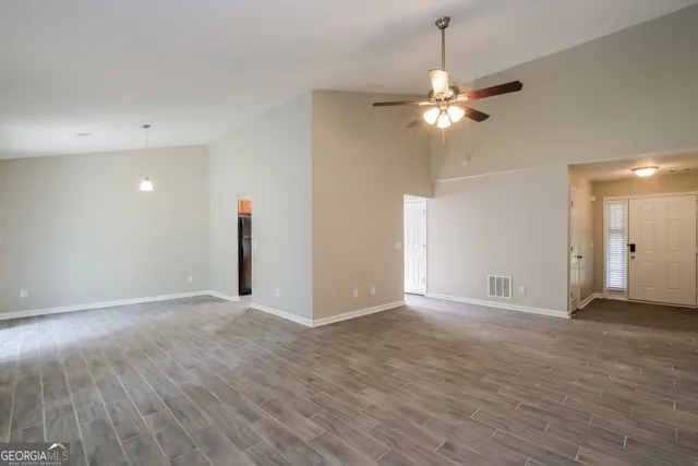 a view of an empty room with chandelier fan and a window