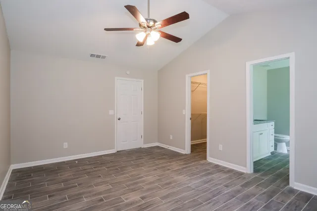 an empty room with wooden floor and a ceiling fan