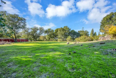 a view of grassy field with benches and trees around