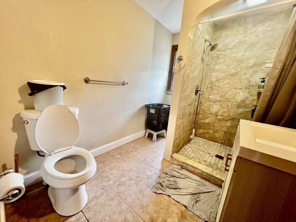 29 Brookfield Road, Unit 1 Sturbridge, MA 01518 - Photo 7 of 9 a white toilet sitting next to a bathroom sink and a mirror