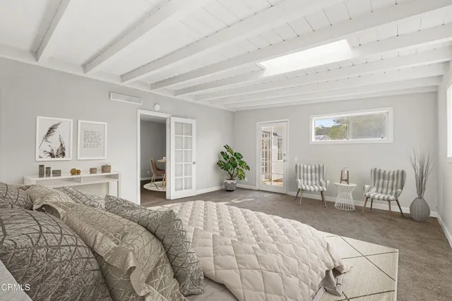 a bedroom with a large bed couch and three windows