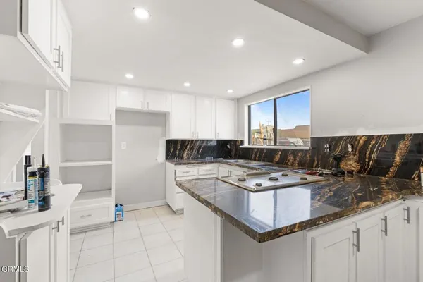 a kitchen with kitchen island granite countertop a sink refrigerator and cabinets