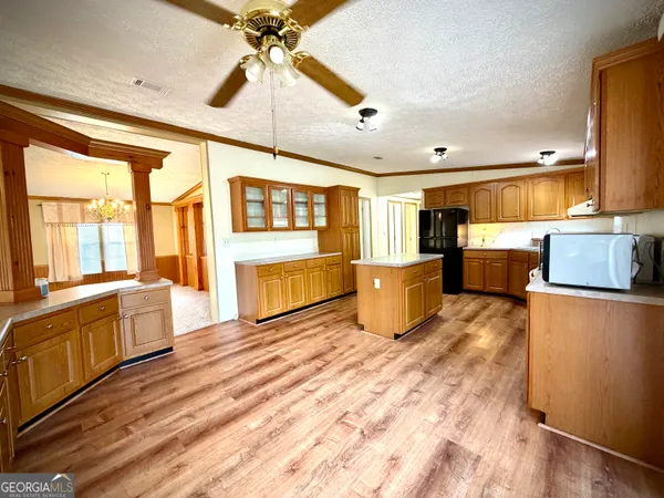 a large kitchen with stainless steel appliances granite countertop a refrigerator a sink dishwasher a stove and a dining table with wooden floor