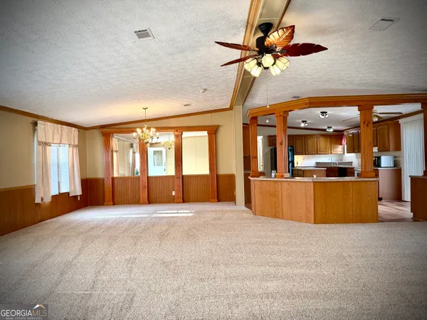 a view of an empty room with window and a kitchen
