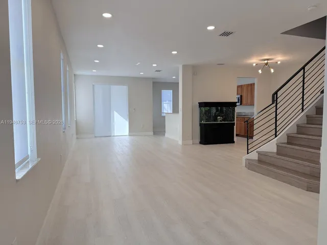 a view of a hallway with wooden floor and a living room