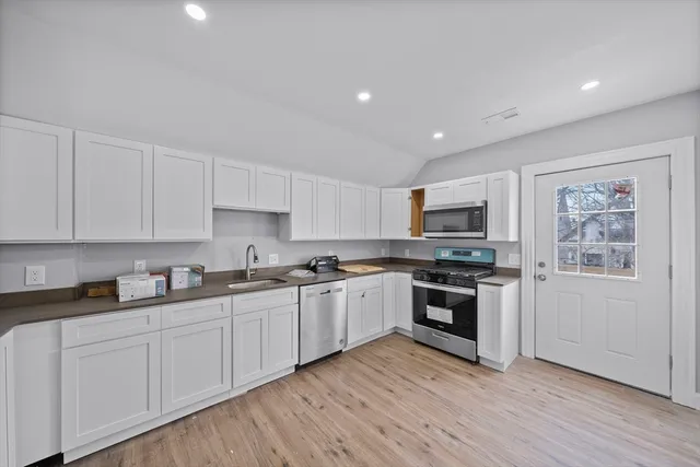 a kitchen with stainless steel appliances granite countertop a stove top oven a sink and white cabinets