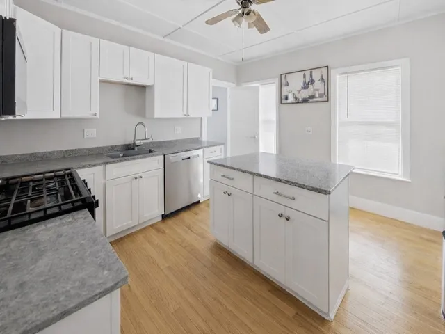 a kitchen with stainless steel appliances granite countertop a stove a sink and white cabinets