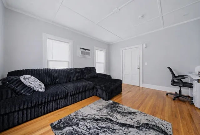 a living room with a bed furniture and a wooden floor