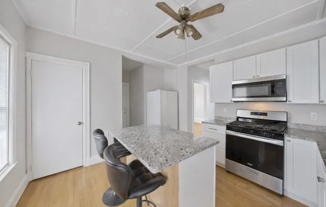 a kitchen with stainless steel appliances granite countertop a stove cabinets and wooden floor