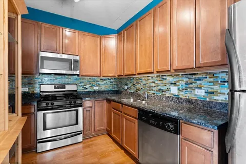 a kitchen with stainless steel appliances granite countertop a stove a sink and a microwave