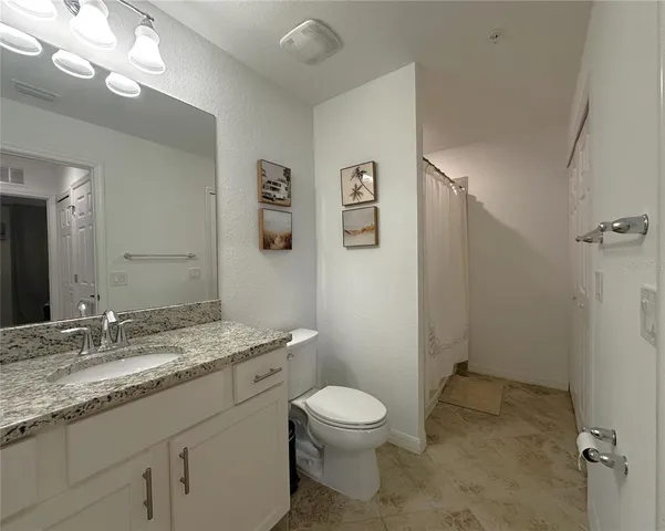 a bathroom with a granite countertop toilet sink and mirror