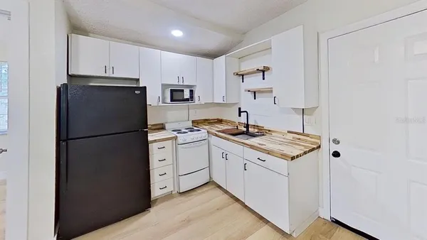a kitchen with a stove a refrigerator and white cabinets