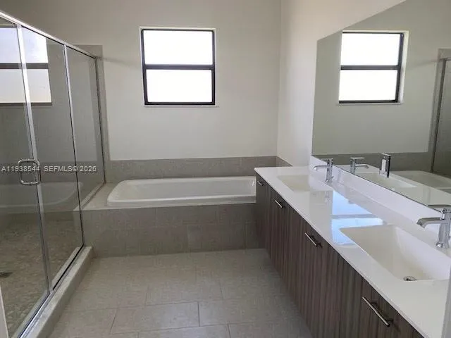 a spacious bathroom with a tub sink and mirror