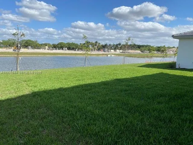 a view of a lake with a yard and large trees