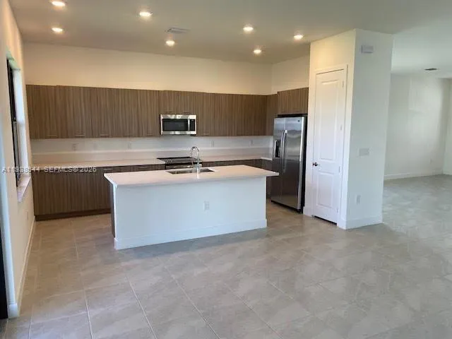 a kitchen with stainless steel appliances granite countertop a sink and a refrigerator