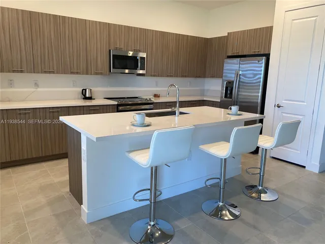 a kitchen with stainless steel appliances granite countertop a sink a stove a refrigerator and a microwave