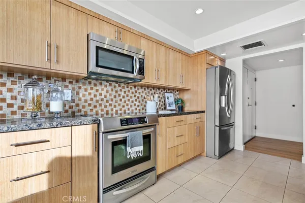 a large kitchen with granite countertop a sink and white cabinets