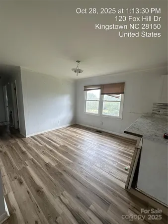 a view of empty room with window and wooden floor