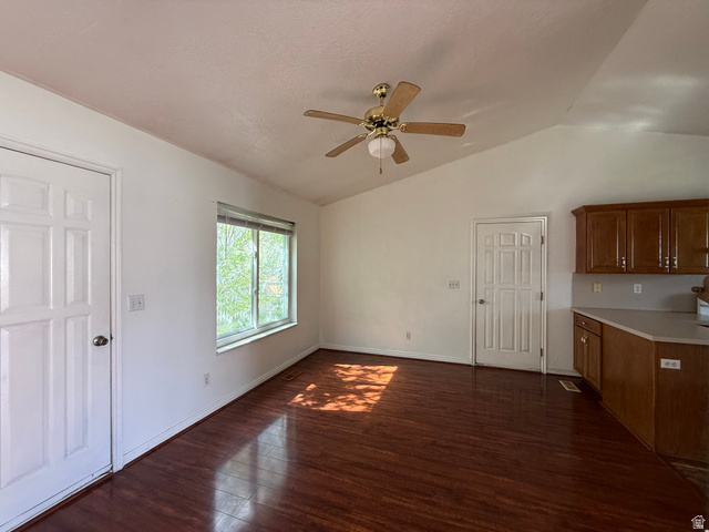 44 Wapiti Loop Hyrum, UT 84319 - Photo 8 of 18 Vaulted ceilings with a ceiling fan, wood-finish flooring, white paneled doors, a window with horizontal blinds, and wood cabinetry with a light-colored countertop