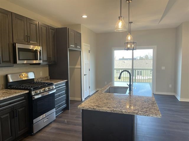 14168 Prairie Commons Lane South Beloit, IL 61080 - Photo 6 of 15 a kitchen with kitchen island granite countertop a stove a sink a oven wooden floor and a window