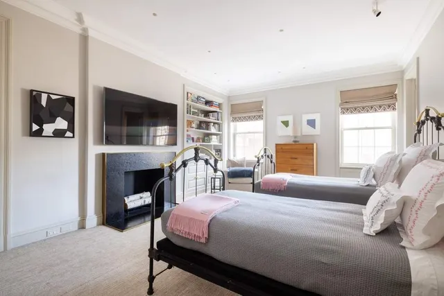a bedroom with bed a flat tv screen and a fireplace