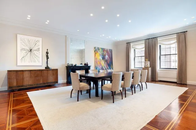 a view of dining room and livingroom with furniture wooden floor a rug a painting and a chandelier