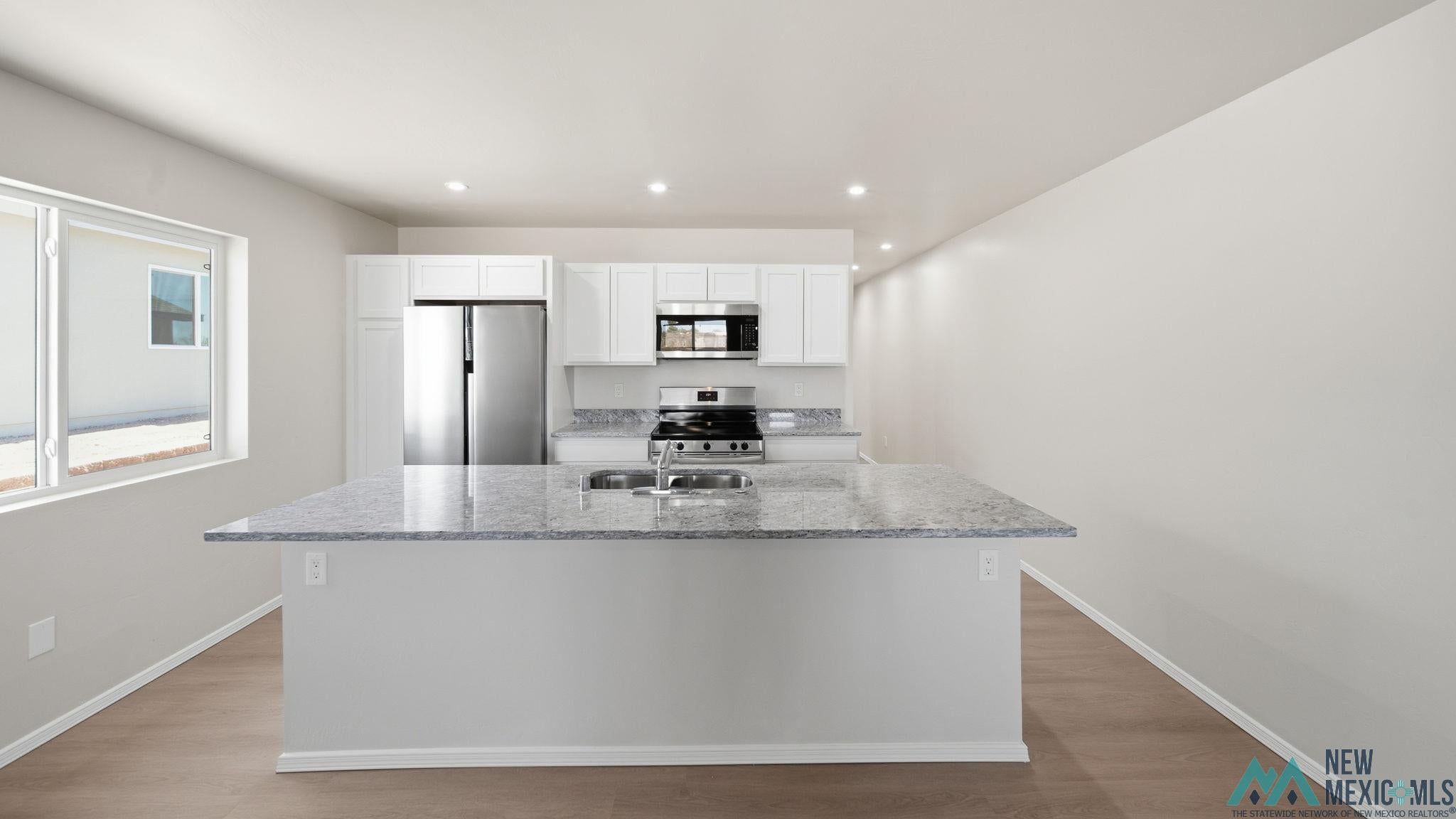 106 Inca Street Elephant Butte, NM 87935 - Photo 16 of 36 Kitchen with stainless steel appliances, white cabinets, a center island with sink, light wood-type flooring, and recessed lighting