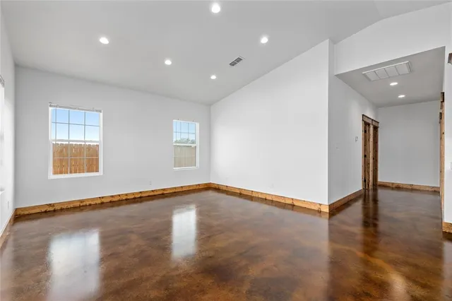 a view of an empty room with window and wooden floor