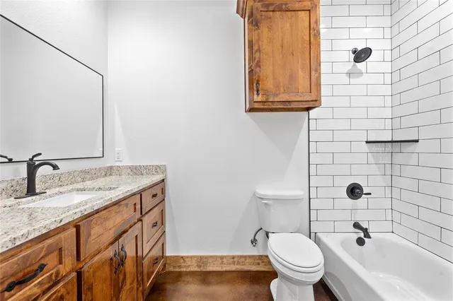 a bathroom with a granite countertop toilet sink and mirror