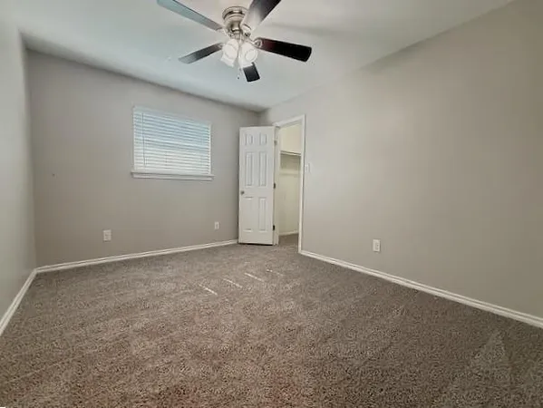 an empty room with a window and a fan
