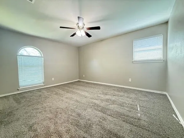 an empty room with windows and fan