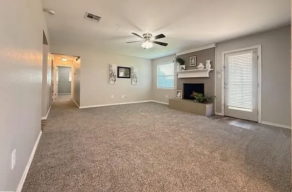 an empty room with windows and fireplace