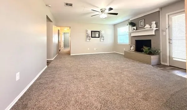 a view of a livingroom with a fireplace a ceiling fan and windows