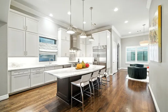 a kitchen with stainless steel appliances granite countertop a stove a refrigerator a sink dishwasher a dining table and chairs with wooden floor