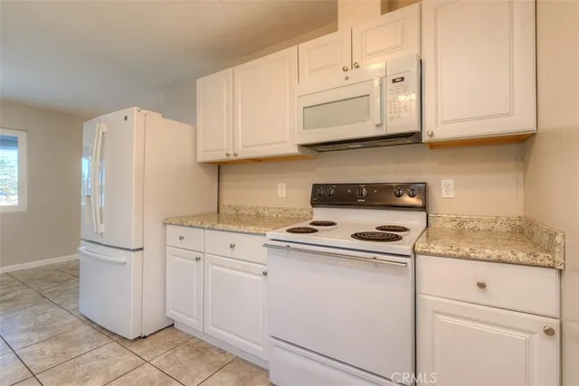 a kitchen with granite countertop white cabinets and refrigerator