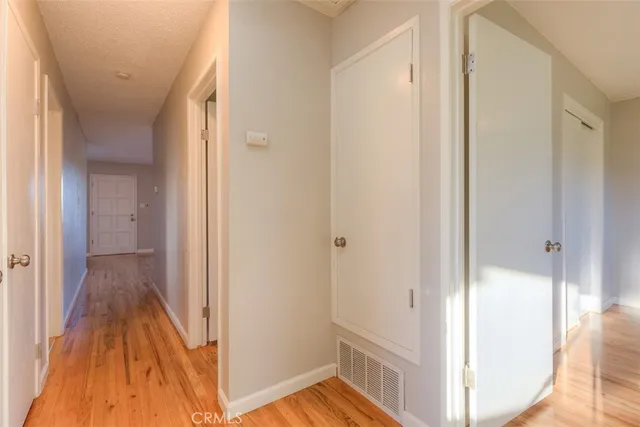 a view of a hallway with wooden floor and a bathroom