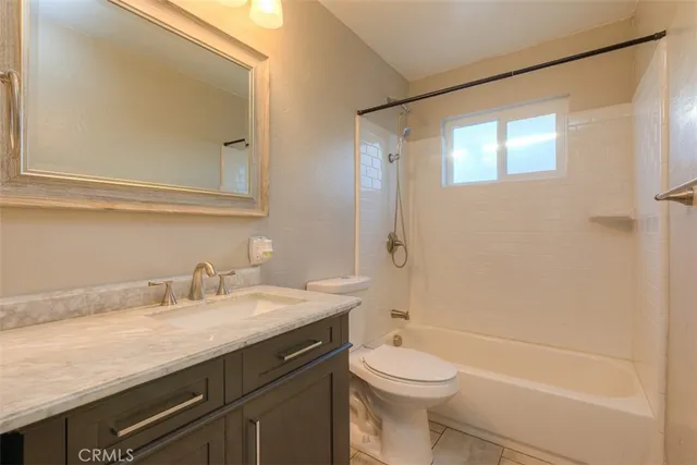 a bathroom with a granite countertop sink a toilet and shower