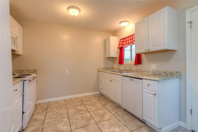 a kitchen with granite countertop a sink cabinets and stainless steel appliances
