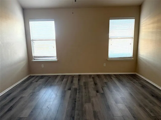 an empty room with wooden floor chandelier fan and windows