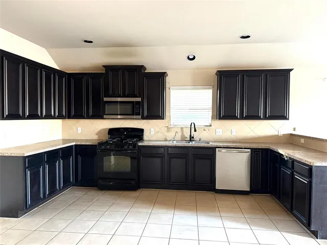 a kitchen with stainless steel appliances granite countertop wooden cabinets a stove top oven a sink and dishwasher
