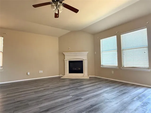 an empty room with ceiling fan and windows