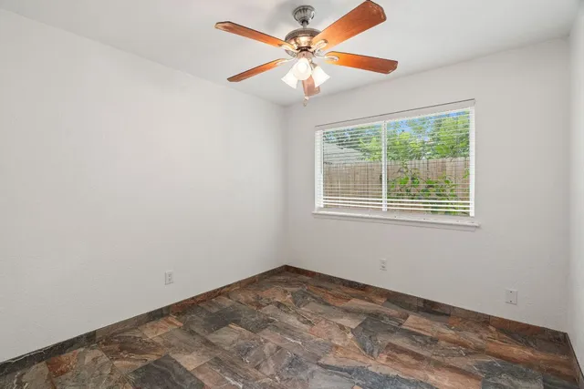 an empty room with a window and a fan