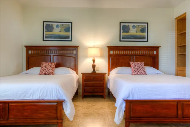 a bedroom with 2 bed and a lamp on dresser