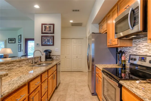 a kitchen with stainless steel appliances granite countertop a sink stove and refrigerator
