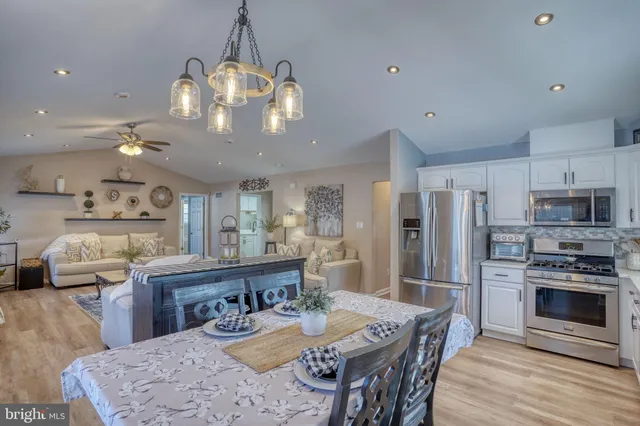 a kitchen with stainless steel appliances granite countertop a sink dishwasher a refrigerator with a dining table and chairs