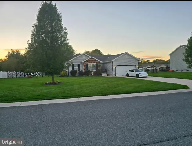 a view of house with a big yard and large trees