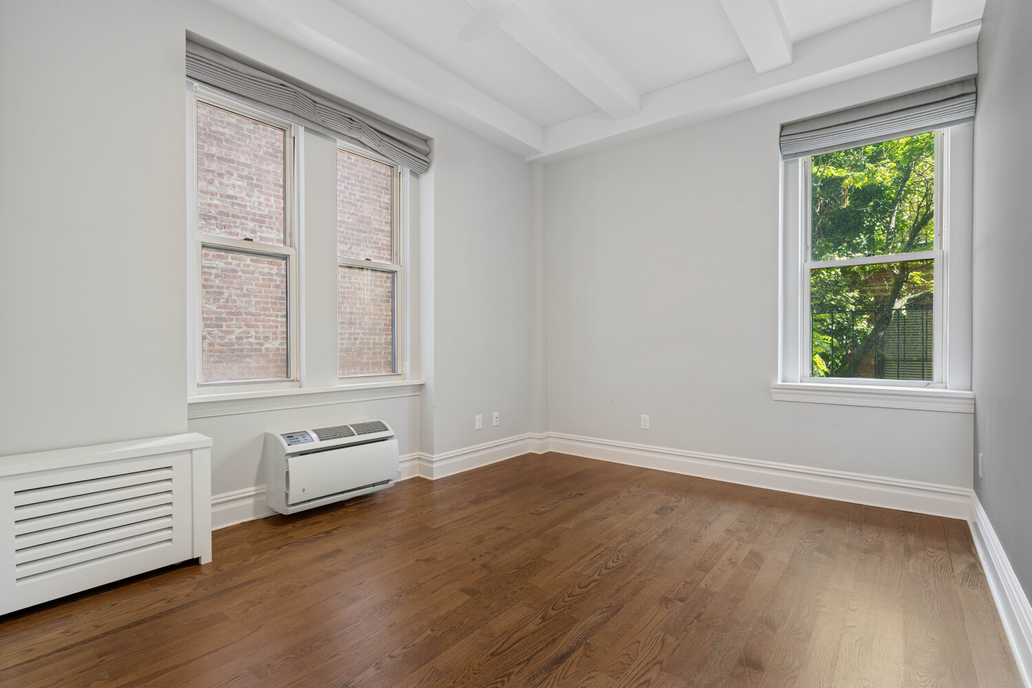 25 5th Avenue, Unit 3G Manhattan, NY 10003 - Photo 4 of 9 an empty room with wooden floor and windows